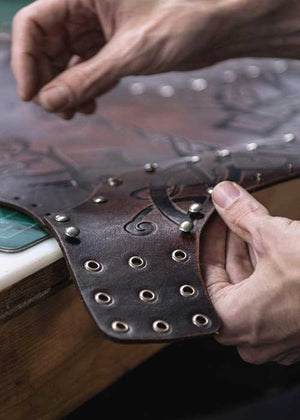 artisan's hand working on a viking leather larp armor